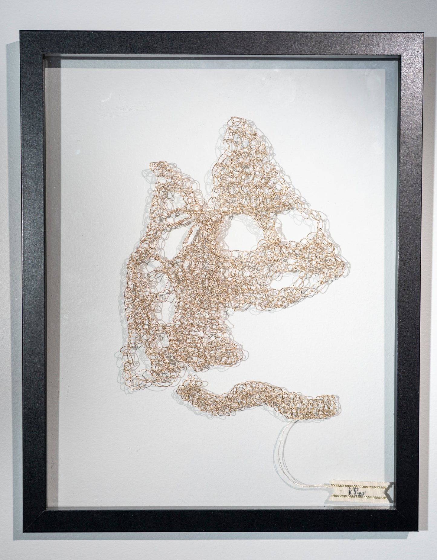 a crocheted golden colored wire that has been hammered flat. It is made into the shape of two mountains and a path leading towards them. They have huge holes in the working and the one in the distance could be interpreted to have a ghostly face screaming. I'm thinking of how they look shiny in the distance but are never what we expect and frequently cause as much harm in the frantic pursuit and abandoned dreams and resultant damage to self