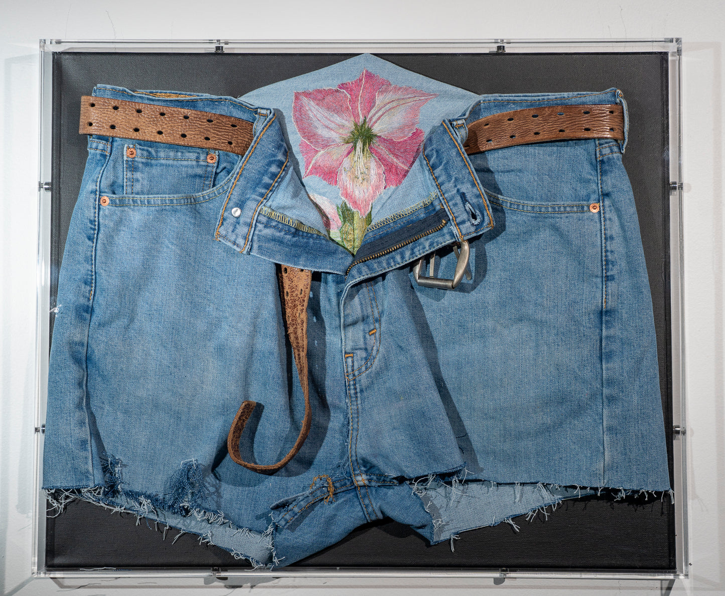 It is a pair of recycled men's jeans with worn leather belt, an open zipper and an amaryllis flower blooming from inside. I was thinking of gender norms and challenging assumptions