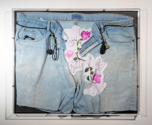 A pair of legless used jeans are displayed with bougainvillea vines erupting from the open zip. They are embroidered onto a frayed piece of cotton and worked into the fabric of the jeans. Through the belt loops are black and green cords that are tied in knots the include a monkeys fist, ranger beads and a pipa knot. The piece is hung in an acrylic display box.